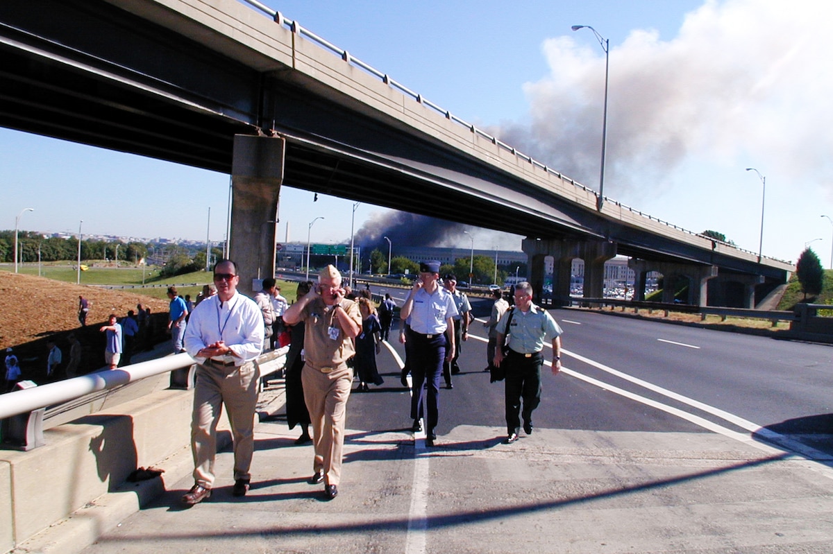Military and civilian personnel walk down a highway after evacuating the Pentagon.