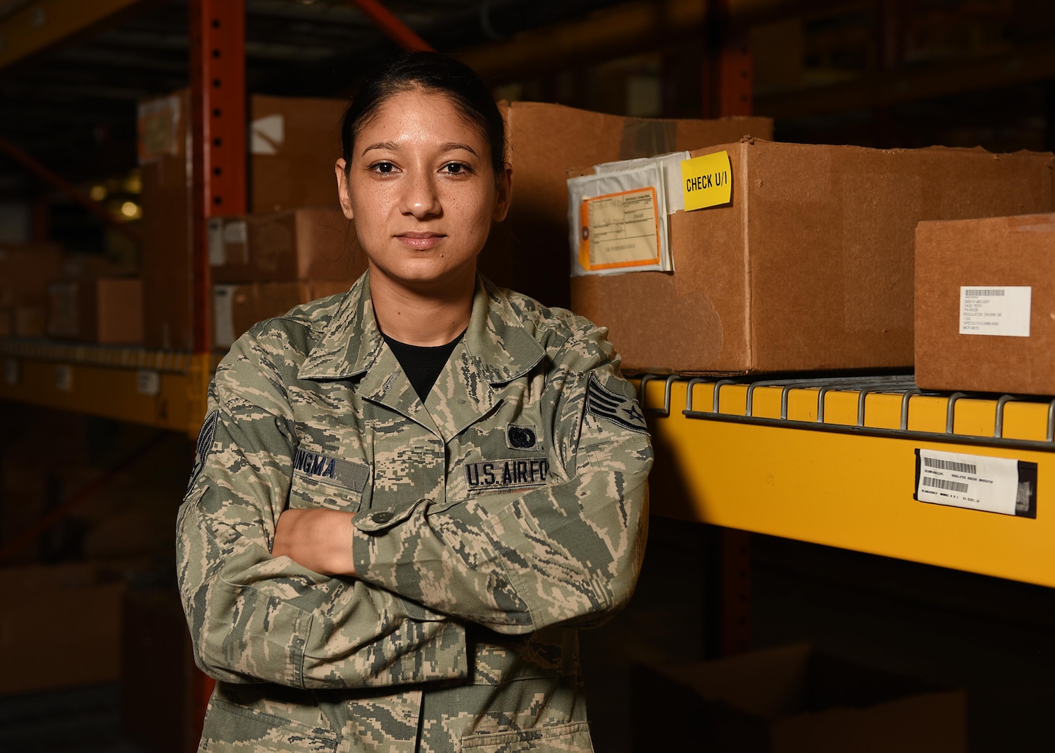 Female staff sergeant poses in front boxes with her arms crossed.