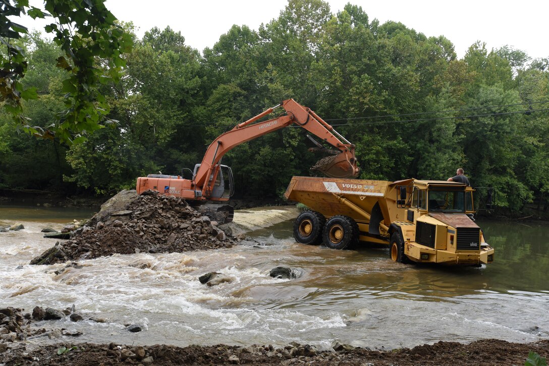 An excavator loads a dump truck with concrete, rock and soil from Roaring River Dam in Jackson County, Tennessee Aug. 1, 2017.