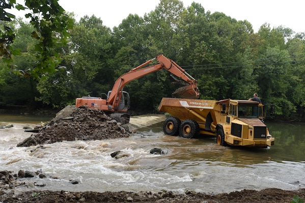 An excavator loads a dump truck with concrete, rock and soil from Roaring River Dam in Jackson County, Tennessee Aug. 1, 2017.