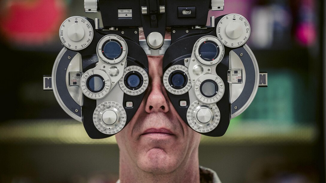 This image shows an airman looking through lenses.