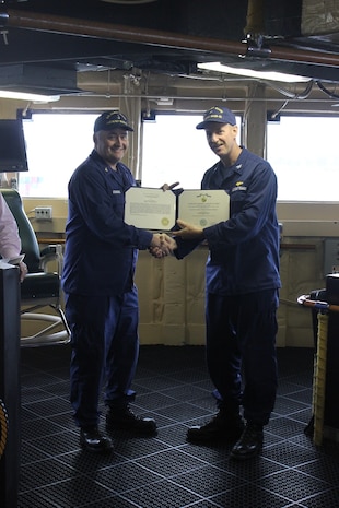 CAPT Tlapa congratulates BMCS Cichoracki as he is awarded the Coast Guard Commendation Medal.