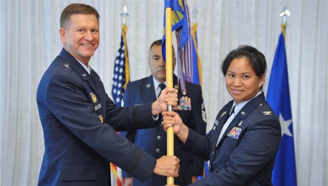 Brigadier General Wayne Monteith presents Colonel Gigi Simko with guidon for change of command ceremony for the 45th Space Wing Medical Group.