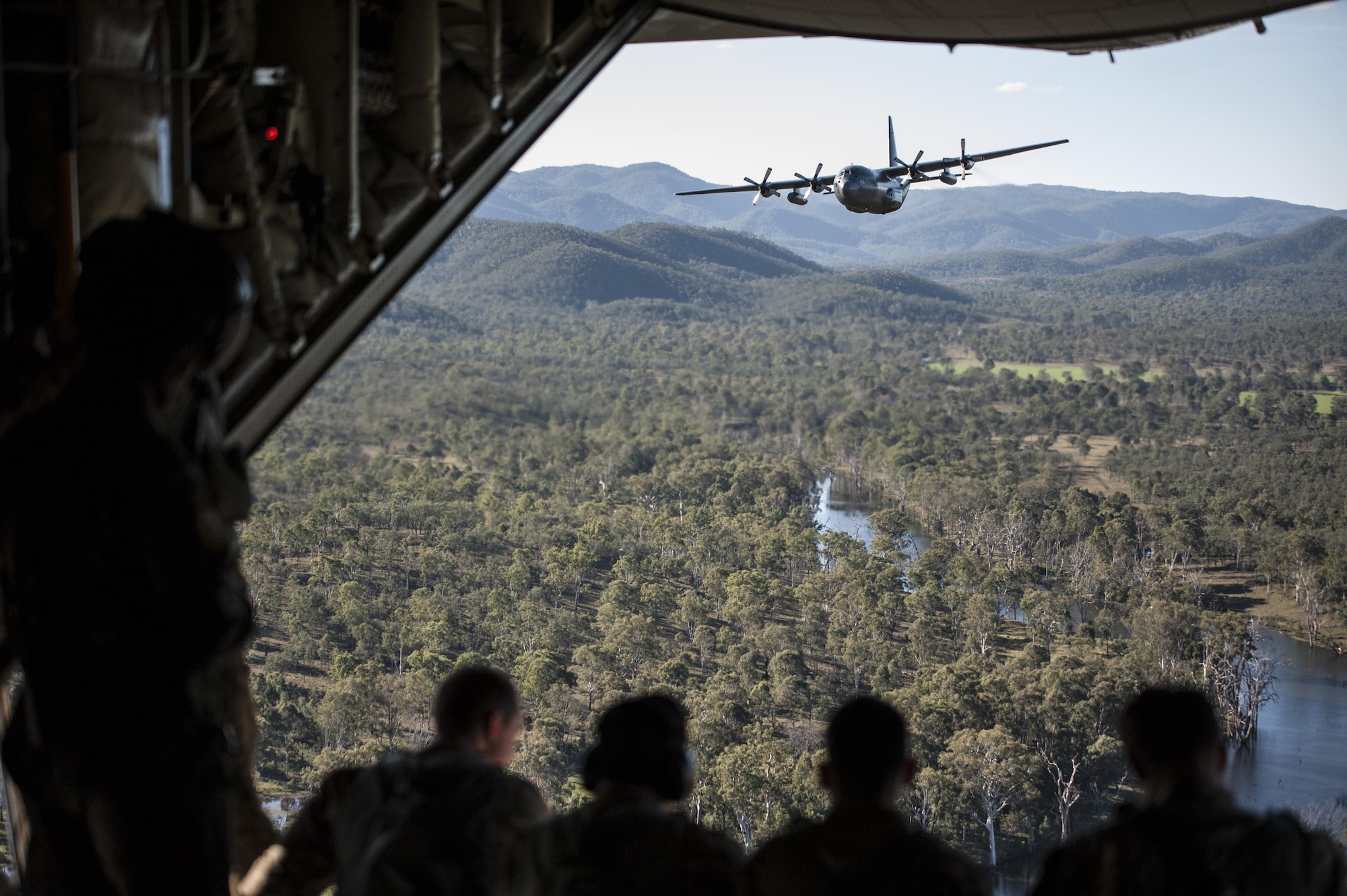 U.S. Air Force 353rd Special Operations Group members look out the back of a U.S. Air Force 17th Special Operations Squadron MC-130J Commando II during a dissimilar formation flight with No. 40 Squadron Royal New Zealand Air Force July 12, 2017, over Queensland, Australia. Executing airborne operations throughout Talisman Saber 2017, the formation flight symbolized the strength of a partnership that has evolved over the years. (U.S. Air Force photo by Capt. Jessica Tait)