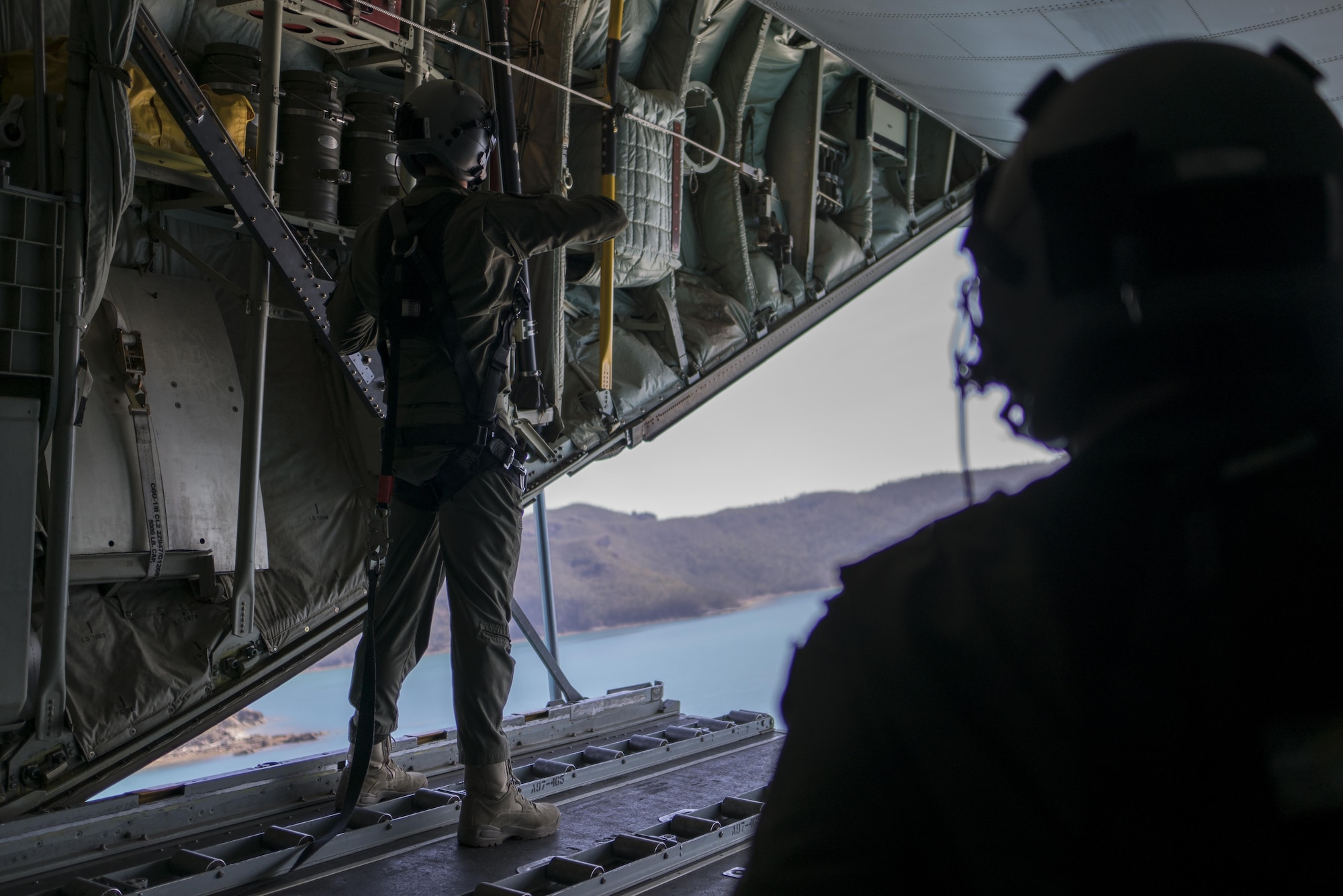 A No. 37 Squadron Royal Australian Air Force loadmasters look out the back of a RAAF C-130J Hercules during a dissimilar formation flight with a U.S. Air Force 17th Special Operations Squadron MC-130J Commando II July 19, 2017, over Queensland, Australia. The bilateral training events performed during Talisman Saber 2017 demonstrate the strength of the alliance between the United States and Australia. (U.S. Air Force photo by Capt. Jessica Tait)