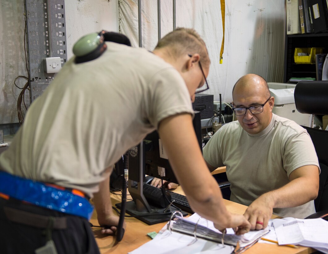 U.S Air Force Tech. Sgt. Juan Pacheco, right, a customer support liaison with the 763rd Expeditionary Aircraft Maintenance Unit, processes an order request for a part at Al Udeid Air Base, Qatar, July 27, 2017.