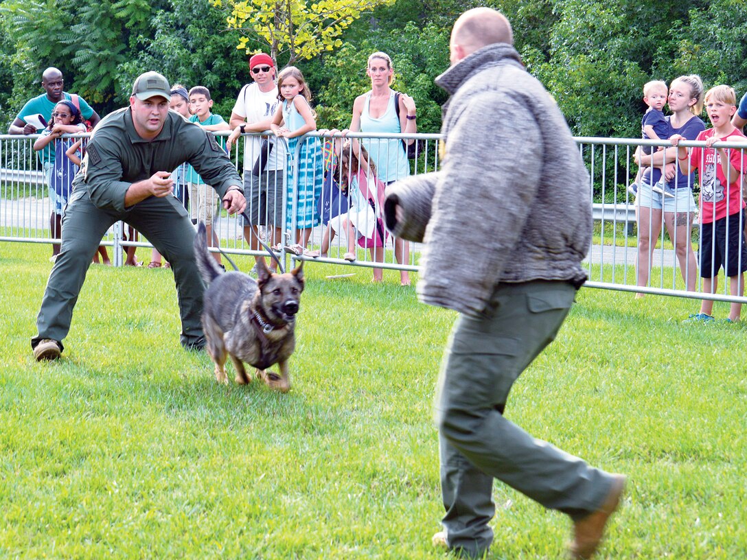The Provost Marshal's Office held a K-9 Unit static display for attendees of the National Night Out to watch. The trainer took the audience through various scenarios to show how the dog is trained to listen to every command.