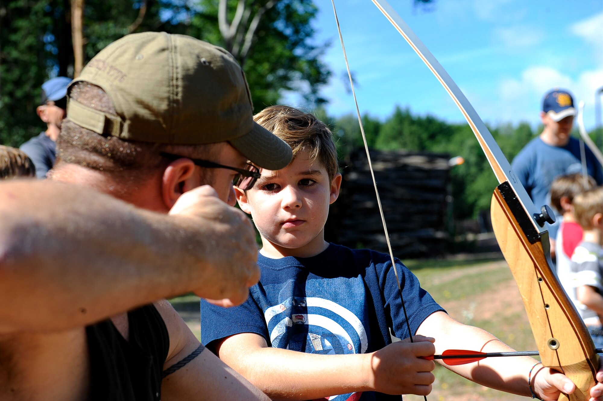 Dominic, son of Tech. Sgt. Thomas Gentry, 603rd Air Operations Center air and air defense noncommissioned officer in charge, listens as Marc Galbraith, 786th Force Support Squadron archery course instructor, demonstrates pulling back the arrow during an Introduction to Archery course at the Kaiserslautern Rod & Gun Club on Vogelweh Military Complex, July 29, 2017. The Kaiserslautern Rod & Gun Club offers courses to educate on weapon safety, various skeet competitions and the necessary skills to shoot moving targets. (U.S. Air Force photo by Airman 1st Class Savannah L. Waters)