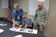 Gerry Cohen, Miami Valley Pet Therapy Association president (left), Cindi Andersen, 88th Medical Center patient advocate (middle) and Maj. Gary Webb, 88th Medical Center critical care flight commander, are reviewing photos of the pet therapy handlers and their dogs who visit the medical center. The Miami Valley Pet Therapy Association is an all-volunteer organization and at the expense of the dog owner, pay for the required certifications, examinations and vaccines.  (U.S. Air Force photo/Stacey Geiger)