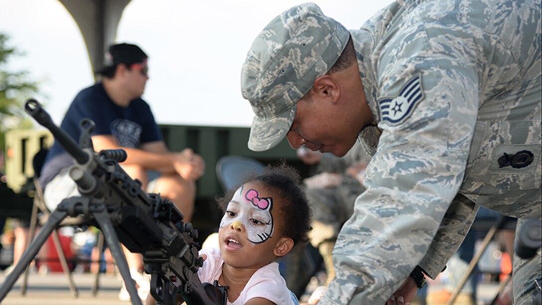 Staff Sgt. Richard A. Elliot, a member of the 177th Fighter Wing’s Security Forces Squadron, shows a community member how to use security forces equipment during Hamilton Township’s National Night Out at the Hamilton Mall in Mays Landing, New Jersey, on Aug. 1, 2017.