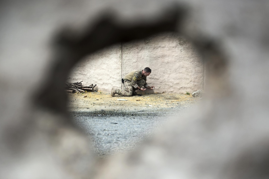 A view through a hole shows a service member collecting evidence.