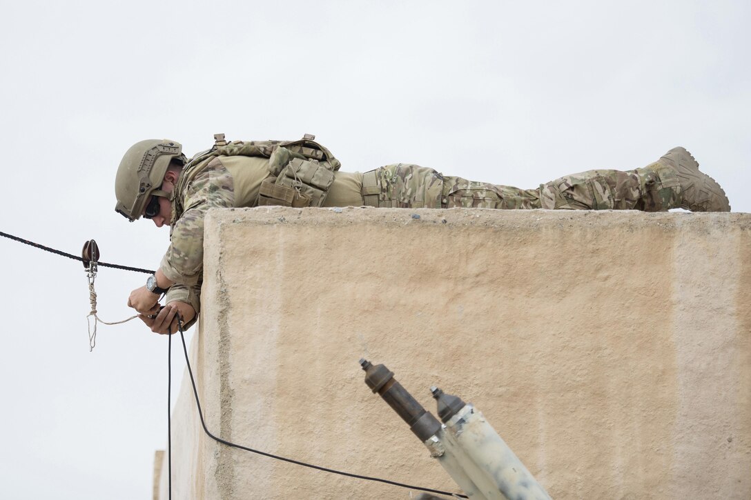 An airmen uses a rope to open a door.