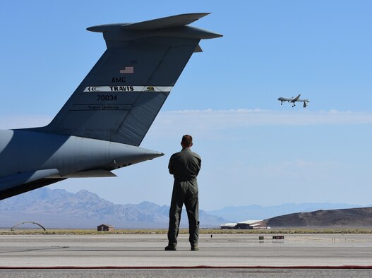 Maj. Richard, 432nd Wing MQ-1 Predator pilot, watches the Predator fly over a C-5M Supergalaxy while reminiscing how about how he became a U.S. Air Force pilot. As a seven-year-old boy, Richard fell in love with the C-5 and aviation during Lethbridge International Airshow in Alberta, Canada. More than twenty years later he became a C-5 pilot, flying for four years in that airframe. Now, he flies the MQ-1 Predator. (U.S. Air Force photo/Senior Airman Christian Clausen)