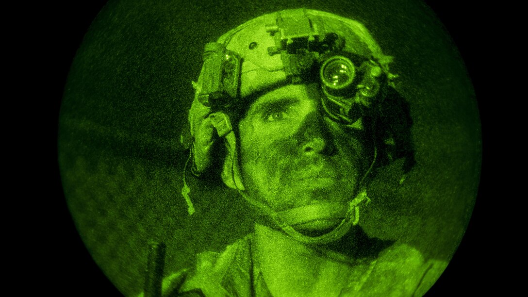 This image shows a soldier in a green light watching troops.