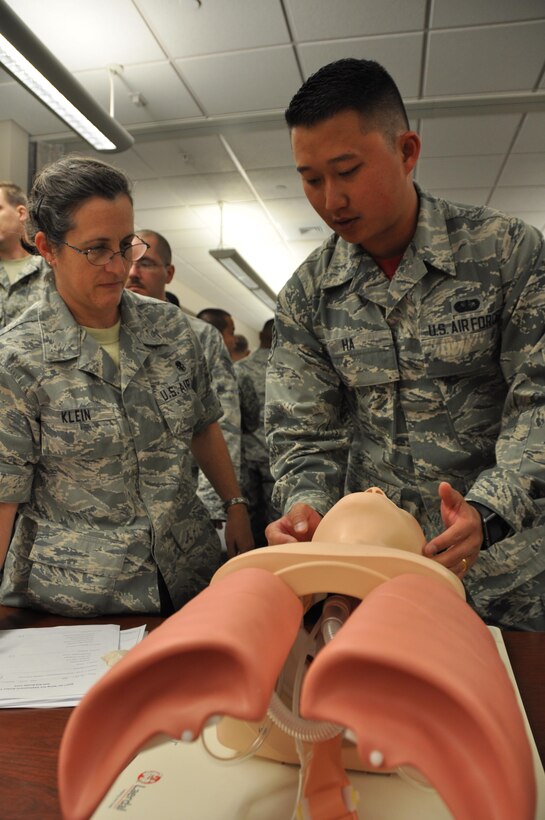 Senior Airman John Ha, 302nd Security Forces Squadron, shows Senior Master Sgt. Karen Klein how to open the airway of an injured person using a training dummy as part of pre-deployment training at Peterson Air Force Base, Colo., July 16, 2017.