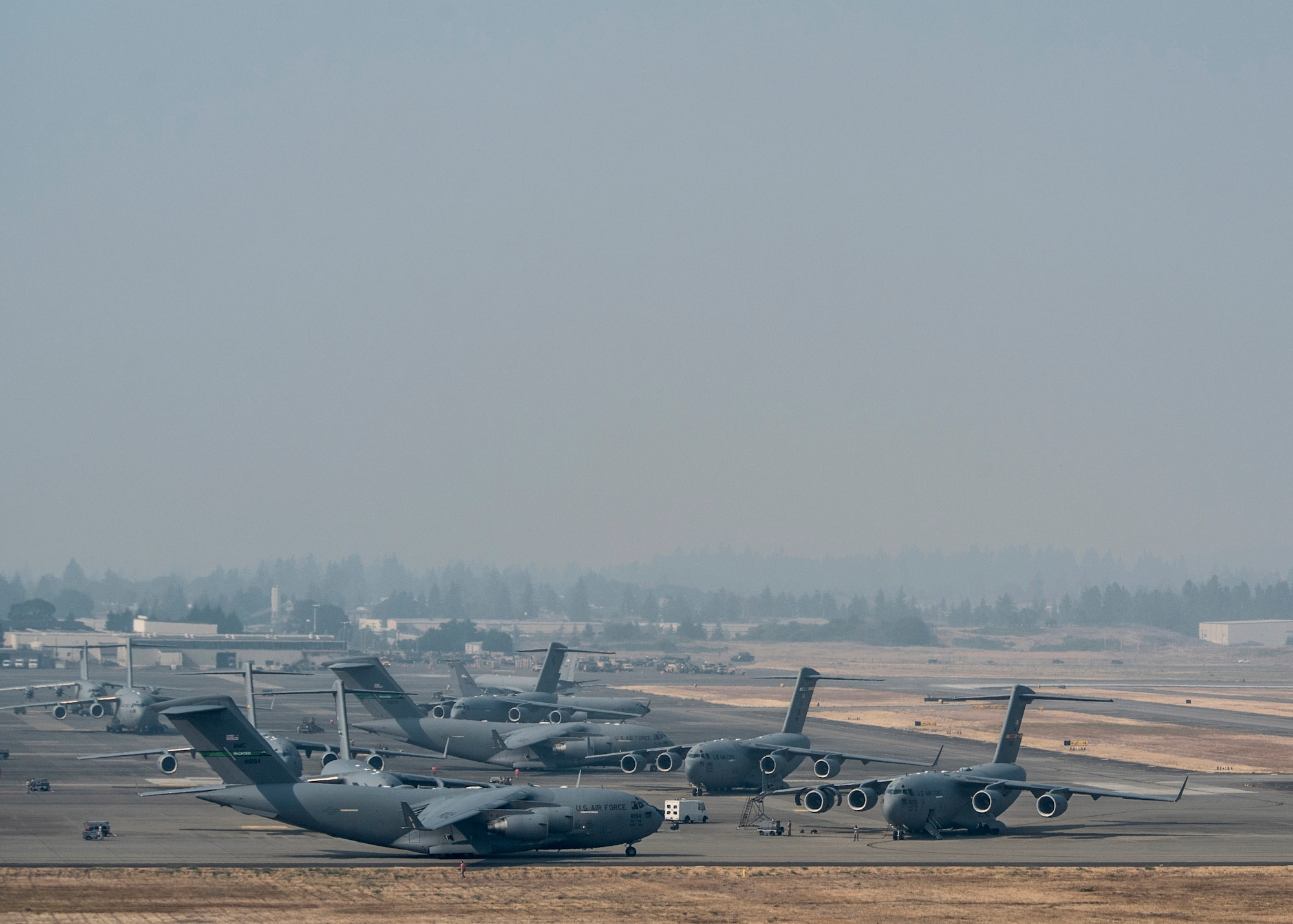 Smoke from the British Columbia, Canada wildfires, which has resulted in a burn ban for the Tacoma area, blankets the Joint Base Lewis-McChord flightline, Aug. 2,2017. The multiple fires have created pollution and visibility concerns for those participating in Mobility Guardian. More than 3,000 Airmen, Soldiers, Sailors, Marines and international partners converged on the state of Washington in support of Mobility Guardian. The exercise is intended to test the abilities of the Mobility Air Forces to execute rapid global mobility missions in dynamic, contested environments. Mobility Guardian is Air Mobility Command's premier exercise, providing an opportunity for the Mobility Air Forces to train with joint and international partners in airlift, air refueling, aeromedical evacuation and mobility support. The exercise is designed to sharpen Airmen’s skills in support of combatant commander requirements. (U.S. Air Force photo by Tech. Sgt. Jodi Martinez)