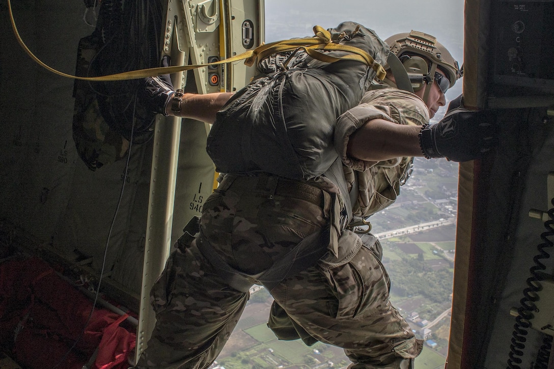 An airman looks out from the open door of an aircraft.