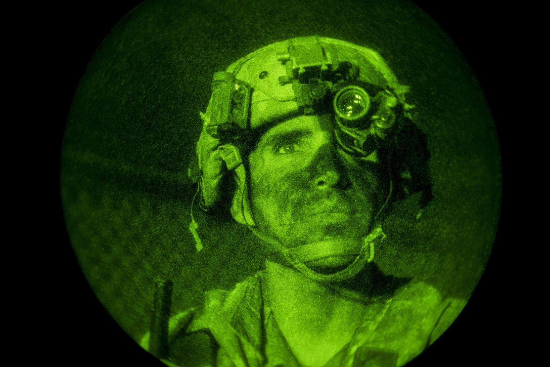 This image shows a soldier in a green light watching troops.