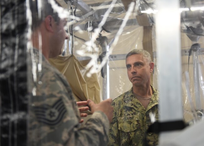 Tech. Sgt. Aaron De L’etoile, left, 628th Medical Group noncommissioned officer in charge of medical maintenance, showcases the Transportation Isolation System Aug. 1 to Rear Adm. Peter Clarke, right, U.S. Transportation Command Strategy, Capabilities, Policy and Logistics Directorate incoming director, during a demonstration as part of an orientation visit here. The TIS is designed to provide aeromedical evacuation for patients with known or suspected exposure to a contagious or infectious disease while protecting aircraft and aircrew. It provides worldwide patient transport capability in case of a biological event. USTRANSCOM is a unified, functional combatant command which provides support to the eight other U.S. combatant commands, the military services, defense agencies and other government organizations by providing full-spectrum global mobility solutions and related enabling capabilities for supported customers’ requirements in peace and war.