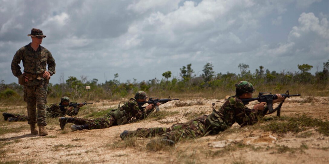 A U.S. Marine infantry trainer watches service members with the Belize Defence Force conduct marksmanship training.
