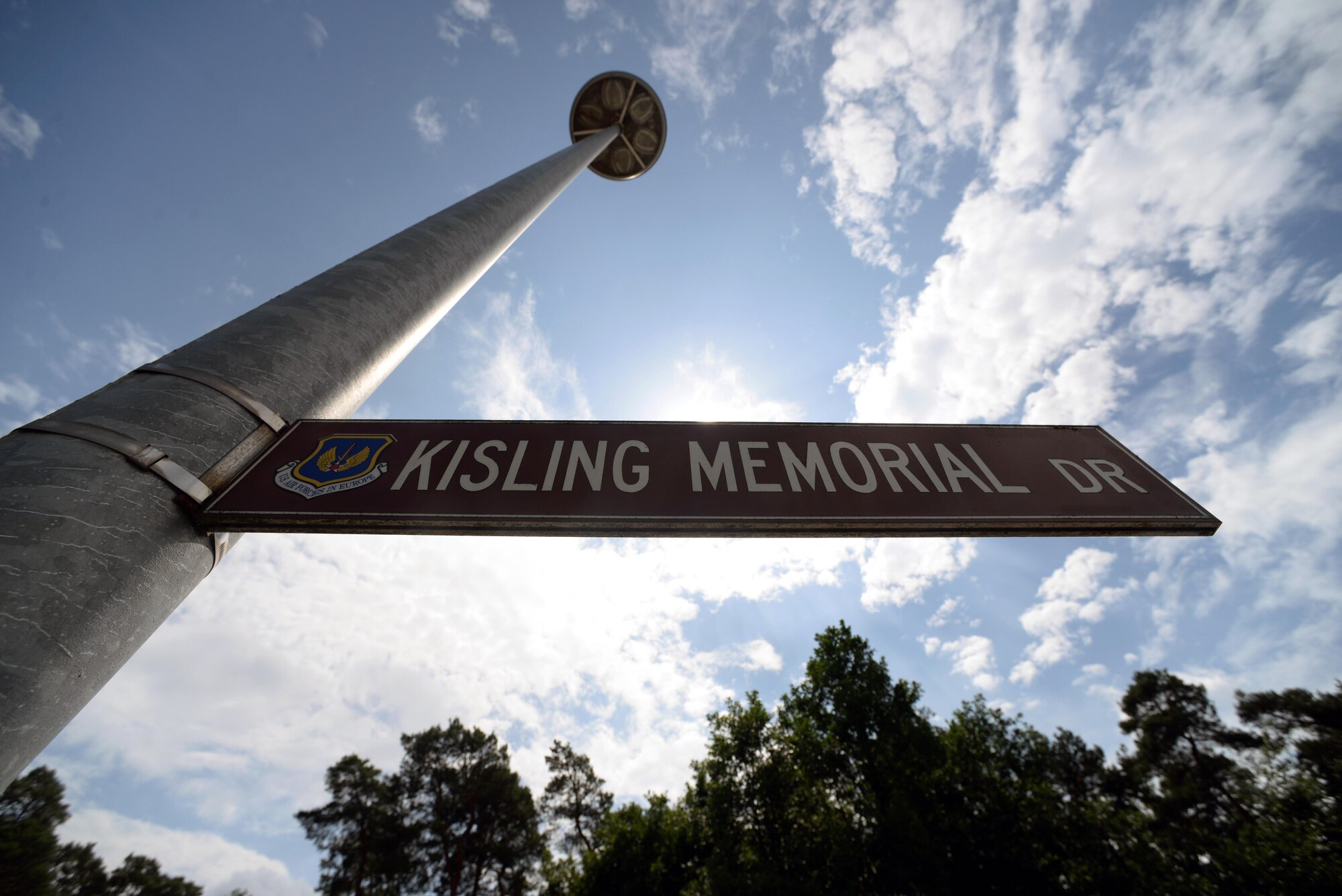 A street sign posts on Ramstein Air Base, Germany, Aug. 3, 2017. Circa 1940, a construction accident of what is today's autobahn 6 left a section of the autobahn that could not be used. The unused autobahn was repurposed as an airstrip by the advancing U.S. Army Air Forces during the final months of World War II. That same strip of road was later used as the airstrip for Landstuhl Air Base in the 1950s. Now, that same location is home to Kisling Memorial Drive, the main road linking the east and west gates of Ramstein Air Base. (U.S. Air Force photo by Airman 1st Class D. Blake Browning)