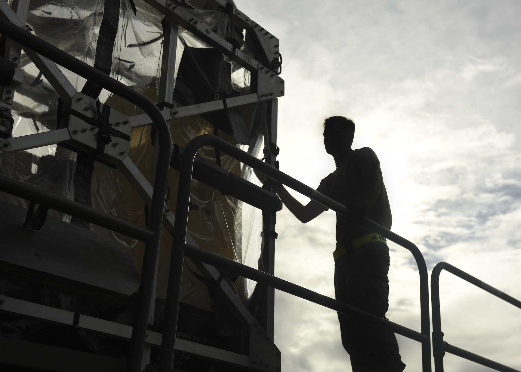 Silhouette of loadmaster loading Transportation Isolation System (TIS)