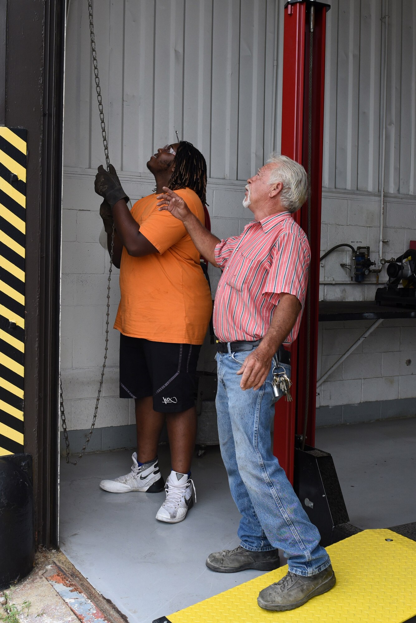 Emmanuel Scott-Persky (left), Goldsboro Summer Youth Employment Initiative Program participant, and Sammy Jones, 4th Civil Engineer Squadron welder, conduct routine maintenance on a vehicle repair shop roll up door, Aug. 3, 2017, at Seymour Johnson Air Force Base, North Carolina.