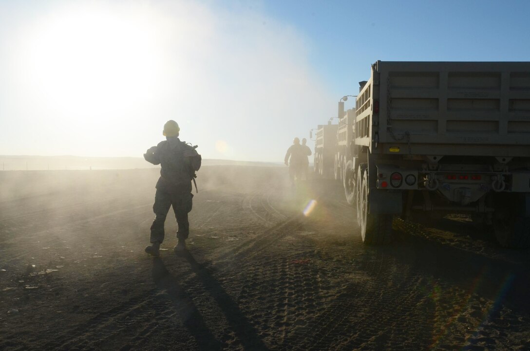 Soldiers walk near their vehicles at a construction site.