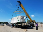 The DLA Distribution Norfolk Pier Operations Team assists the Norfolk Air Mobility Command Air Terminal to lift a 21-ton sonar dome in order to prepare it for flight in a C5 cargo aircraft.