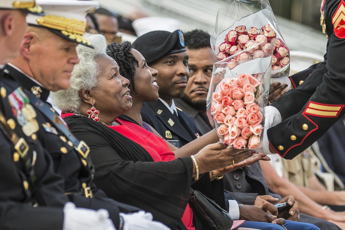A Marine present flowers to the mother of a Marine during his retirement ceremony.