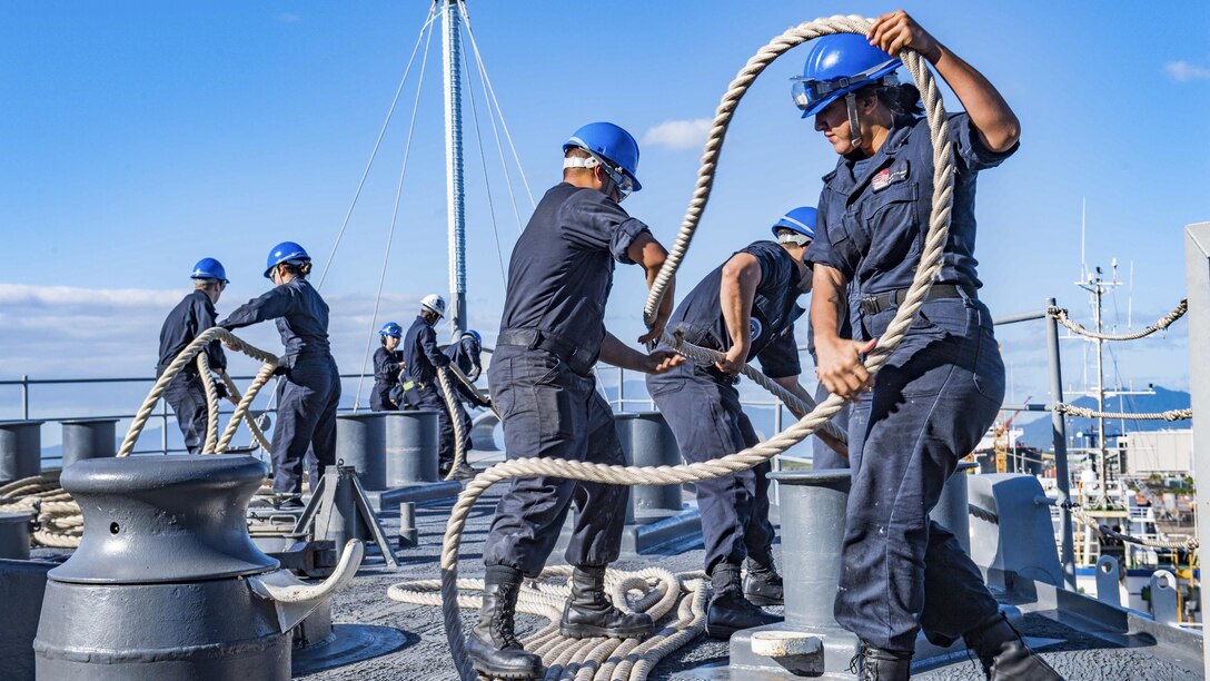 Sailors handle ropes aboard a ship.