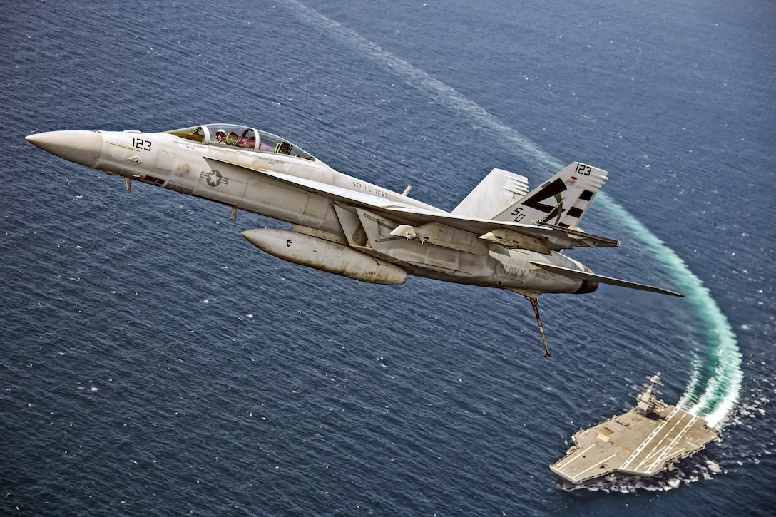 An aircraft flies over a ship in the ocean.