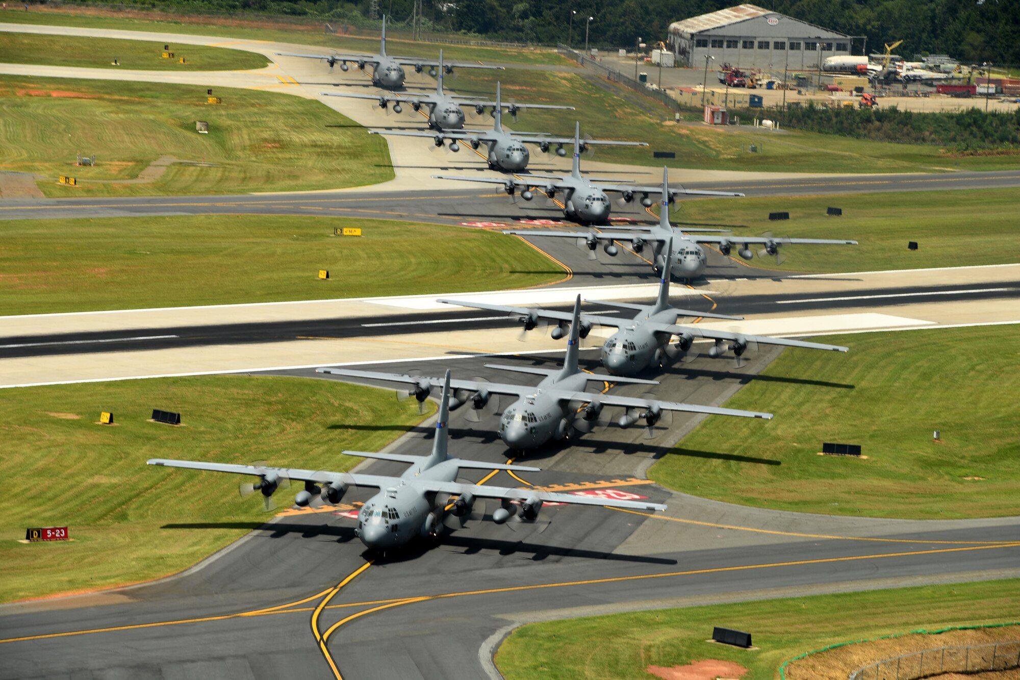 Eight C-130 aircraft taxi down the runway