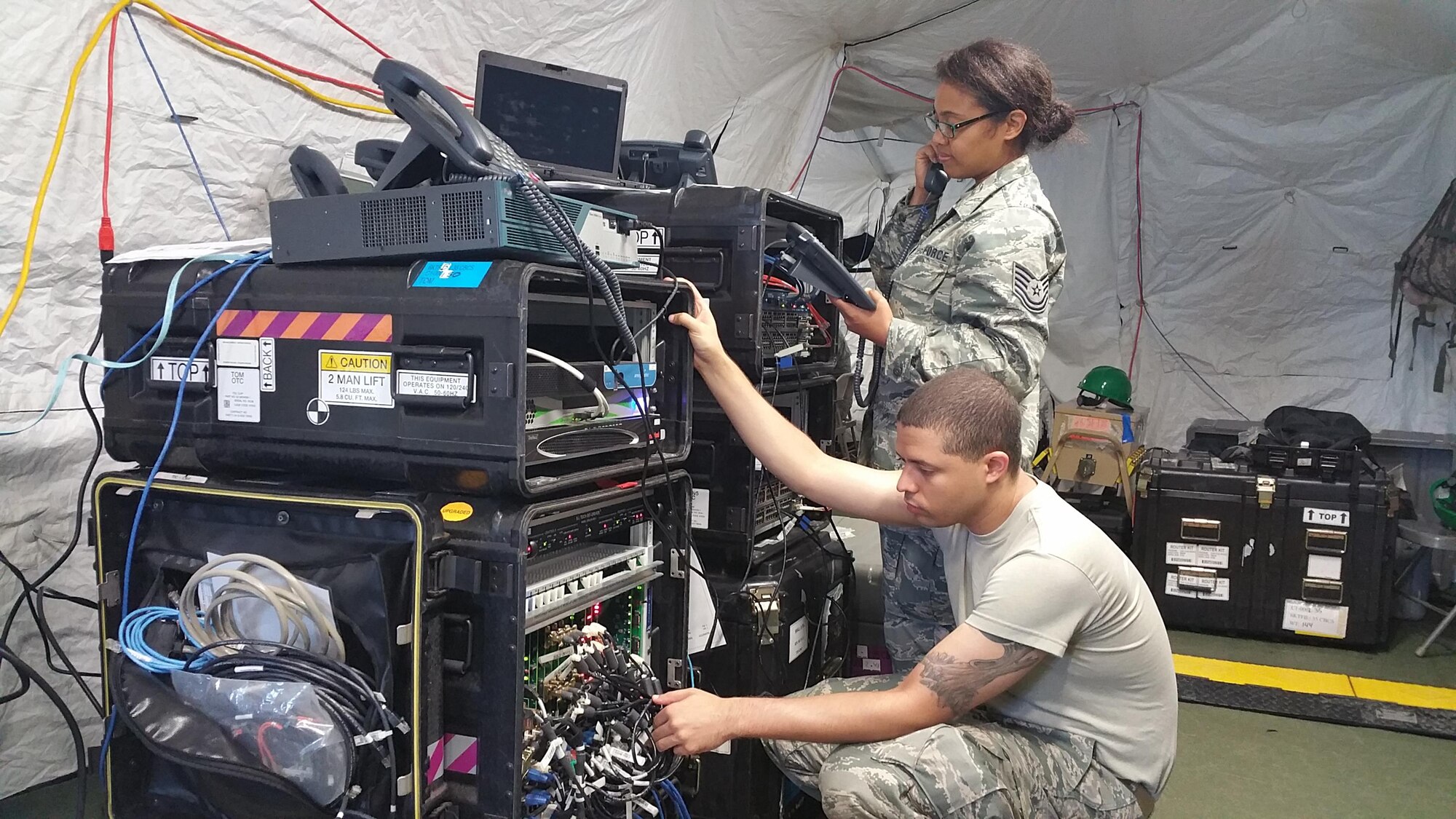 Two Citizen Airmen assigned to the 35th Combat Communications Squadron, test a deployable Voice over Internet Protocol (VoIP) phone switch in a simulated deployed environment during their annual tour at Homestead Air Reserve Base, Fla.