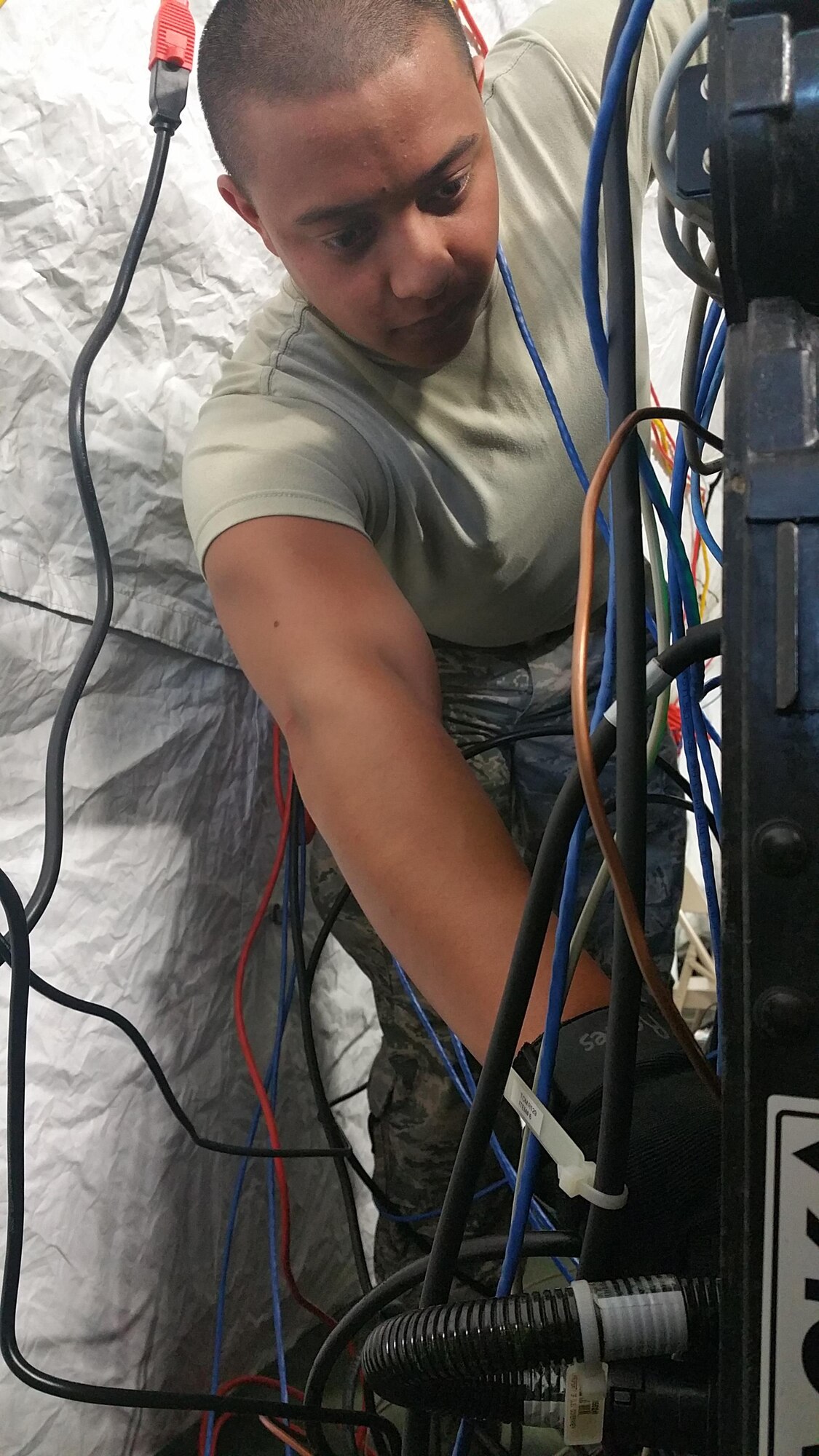 A Citizen Airman connects cabling to provide voice and data services to geo-separated tents across a simulated-deployed location at Homestead Air Reserve Base, Fla.