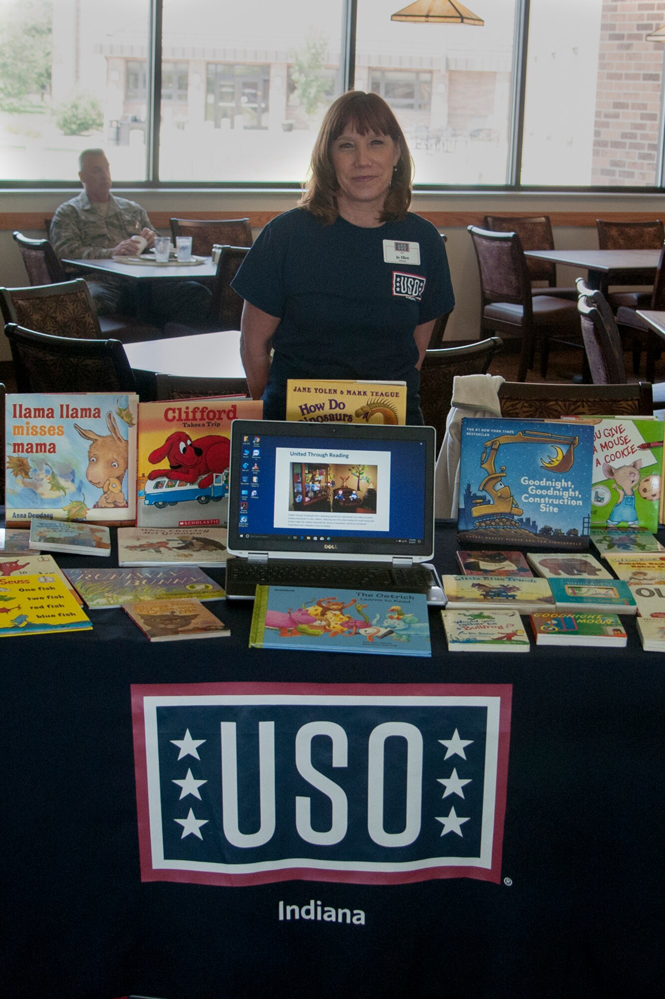 Jo Ellen Roll, USO volunteer, poses with the books available to service members as part of the United Through Reading program at Grissom Air Reserve Base, Indiana on August 5, 2017. The program allows service members to record themselves reading a book for their children then send a copy of the recording and the book to their families so they can stay connected even when they are not home. (U.S. Air Force photo/Staff Sgt. Dakota Bergl)