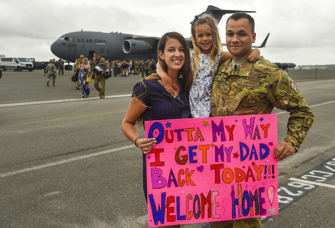 Tech. Sgt. Jason Fatjo, 14th Airlift Squadron loadmaster, and his family hold his welcome home sign at Joint Base Charleston, S.C., Aug. 8, 2017. Fatjo returned from a deployment to Southwest Asia.