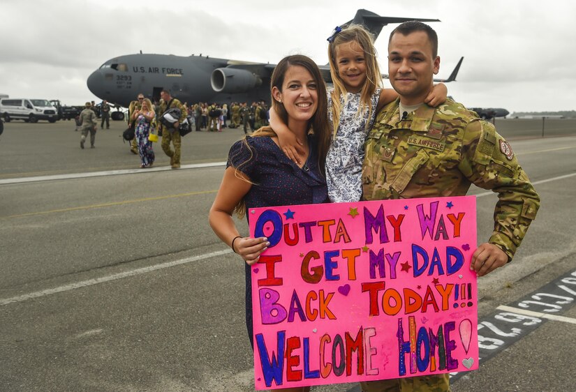Tech. Sgt. Jason Fatjo, 14th Airlift Squadron loadmaster, and his family hold his welcome home sign at Joint Base Charleston, S.C., Aug. 8, 2017. Fatjo returned from a deployment to Southwest Asia.
