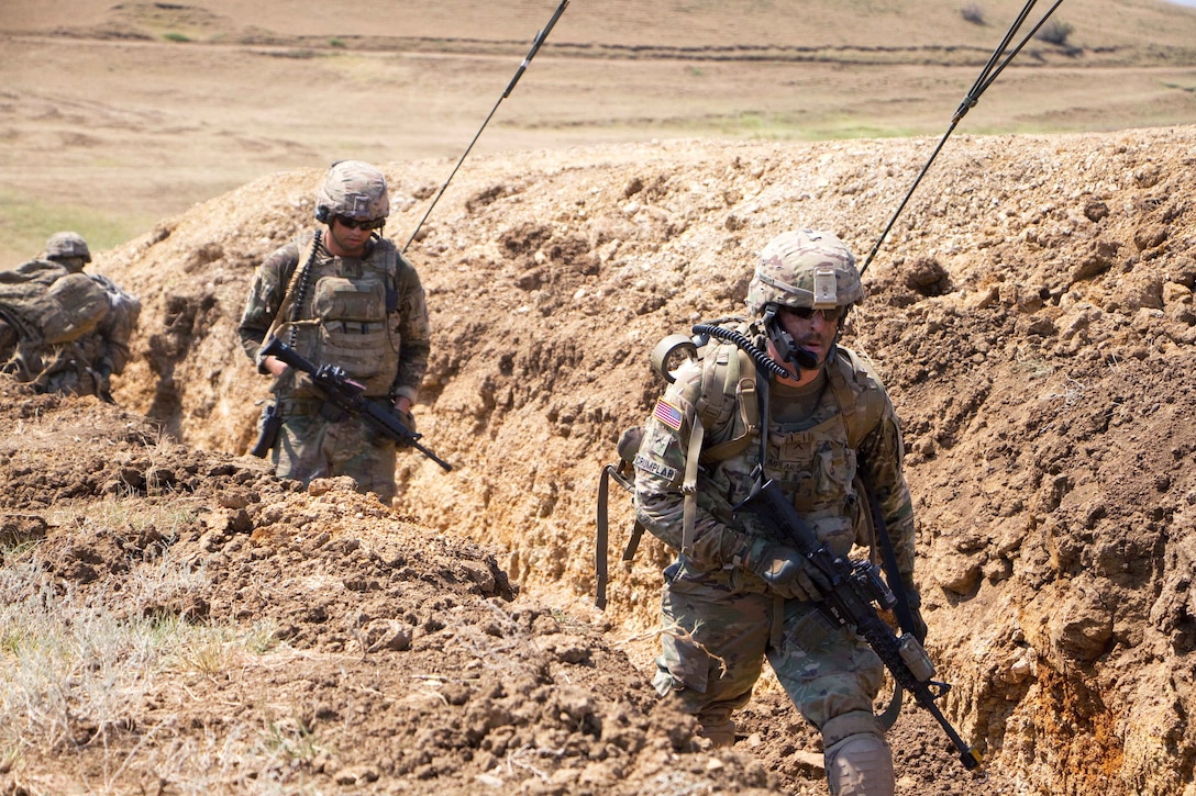 Soldiers walk through a trench while on a dismounted patrol.