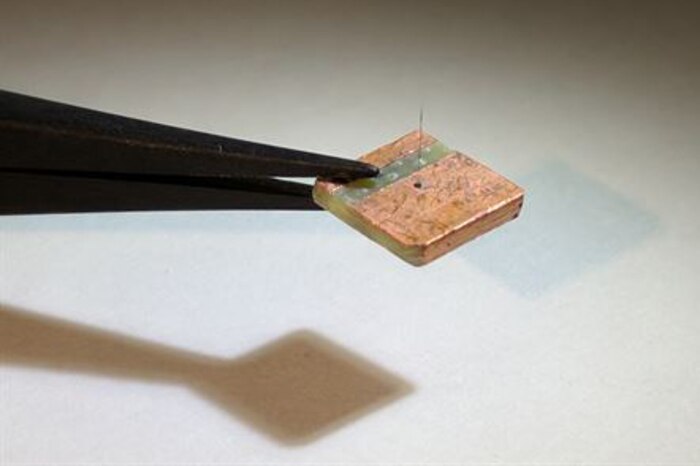 Tweezers hold a small square platform with a artificial hair sensor.