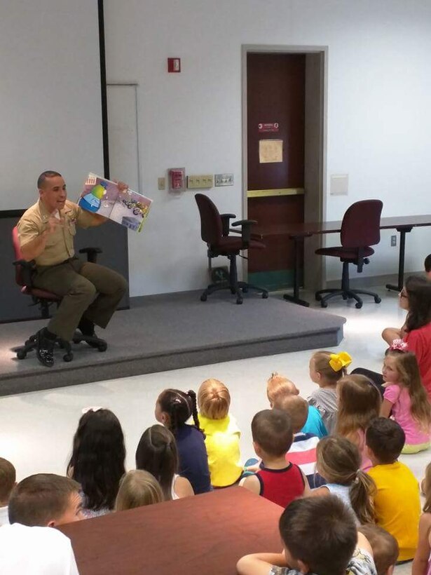 Captain Trodden, Operations Officer for PMO, reading to the boys and girls at Ellis Hall. Security Battalion personnel were on hand to read books and participate in a show-and-tell to youngsters who attended for Police and Firefighter Storytime.