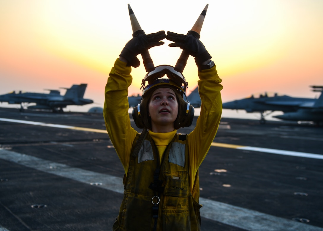 Aircraft carrier sailor signals to pilot
