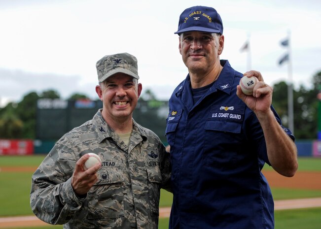 U.S. Air Force Col. Patrick Winstead, 437th Airlift Wing vice commander, left, and U.S. Coast Guard Capt. Gregory Stump, Coast Guard Sector Charleston commander, right, hold up their souvenir baseballs after throwing the ceremonial first pitches during the Charleston RiverDogs Military Appreciation Night at Joseph P. Riley Jr. Park, Aug. 3, 2017.