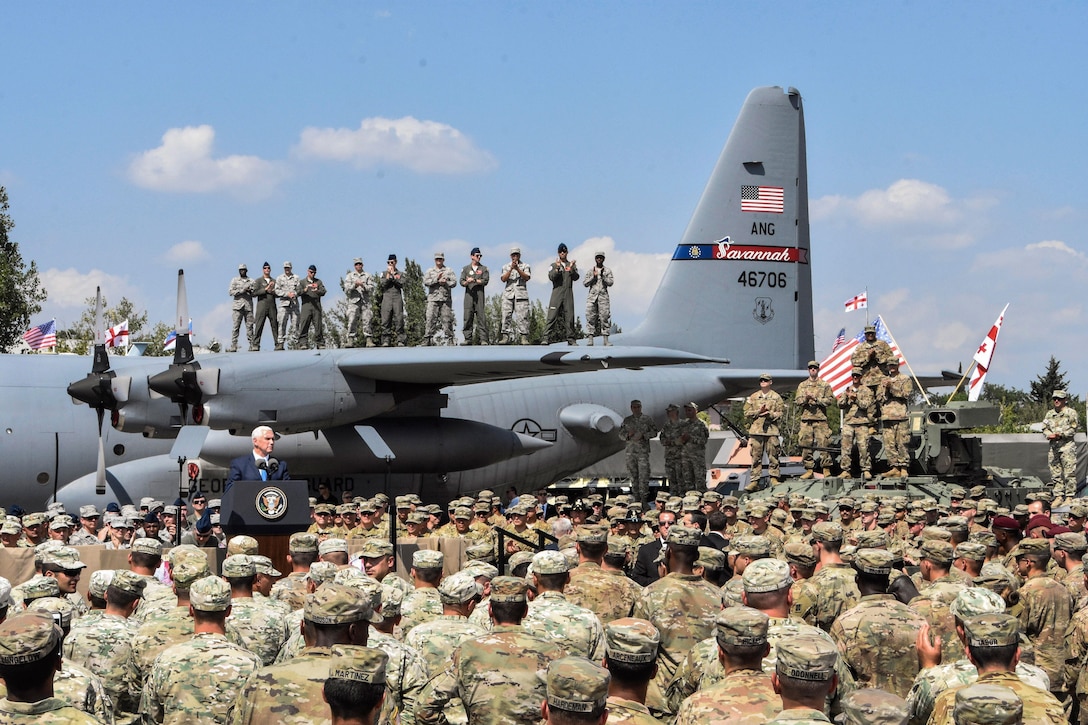 Vice President Mike Pence speaks to a crowd of troops in front of an aircraft.