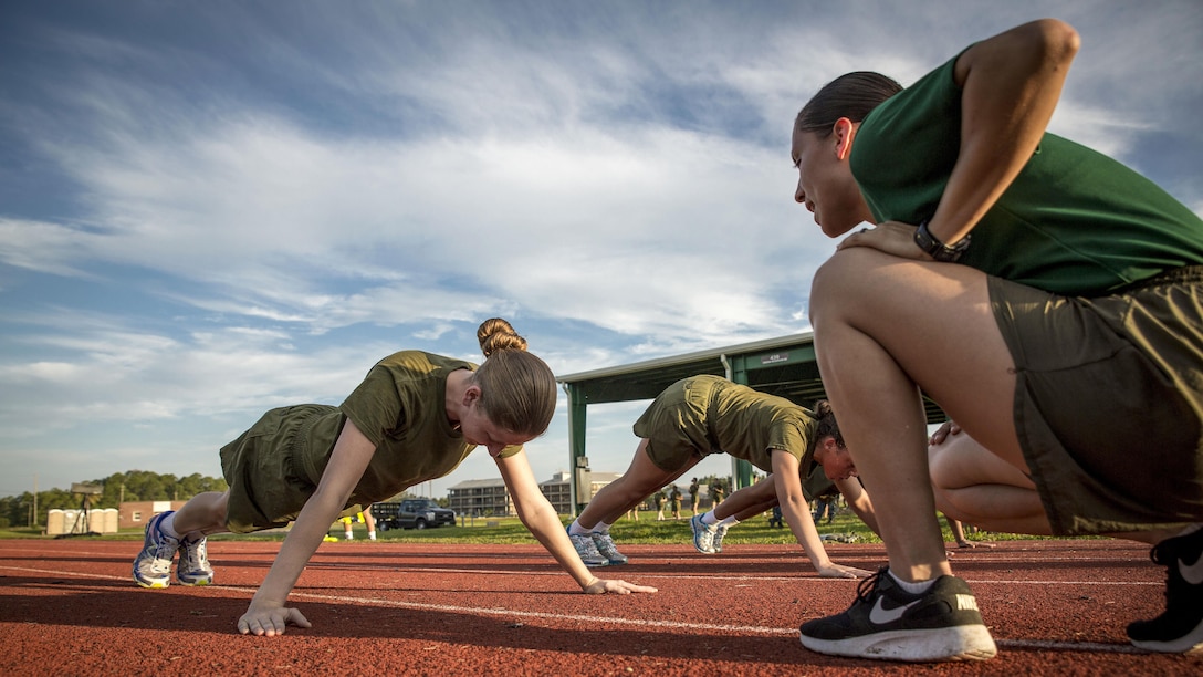 An instructor monitors as Marine Corps recruits do pushups.