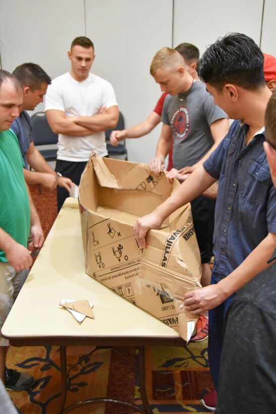 Airmen from the 931st Aircraft Maintenance Squadron construct a boat from cardboard and tape as part of a team building exercise during Wingman Day, Aug. 6, 2017, at McConnell Air Force Base, Kan.  In contrast to years past, Airmen were grouped with people from within their units for the team building exercises.  The exercise took place at the Dole Center. The boats had to be completed within a short amount of time.  (U.S. Air Force photo by Tech. Sgt. Abigail Klein)