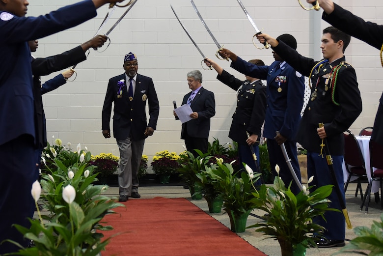 A Purple Heart recipient walks through the Wayne/Goldsboro Purple Heart Banquet walk of honor saber salute conducted by Junior ROTC cadets, Aug. 4, 2017, at the Goldsboro/Wayne Purple Heart Foundation Purple Heart banquet in Goldsboro, North Carolina.