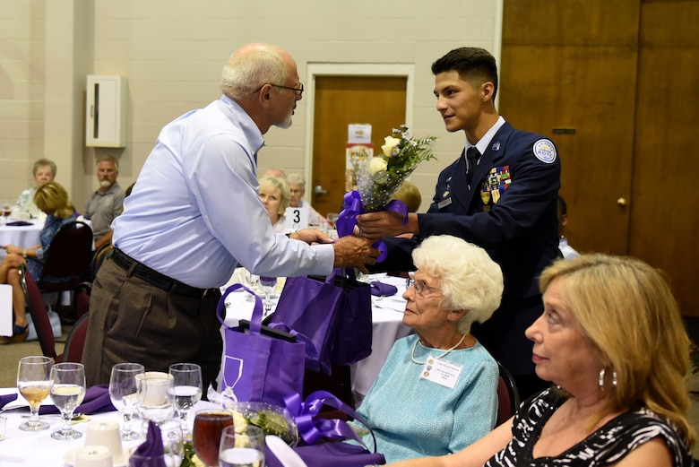 John Lane (left), a Gold Star brother, receives a bouquet of flowers and a gift bag presented by a Junior ROTC cadet, Aug. 4, 2017, at the Goldsboro/Wayne Purple Heart Foundation Purple Heart banquet in Goldsboro, North Carolina.