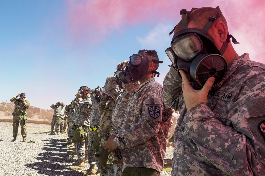 Soldiers wear masks as pink smoke wafts overhead.