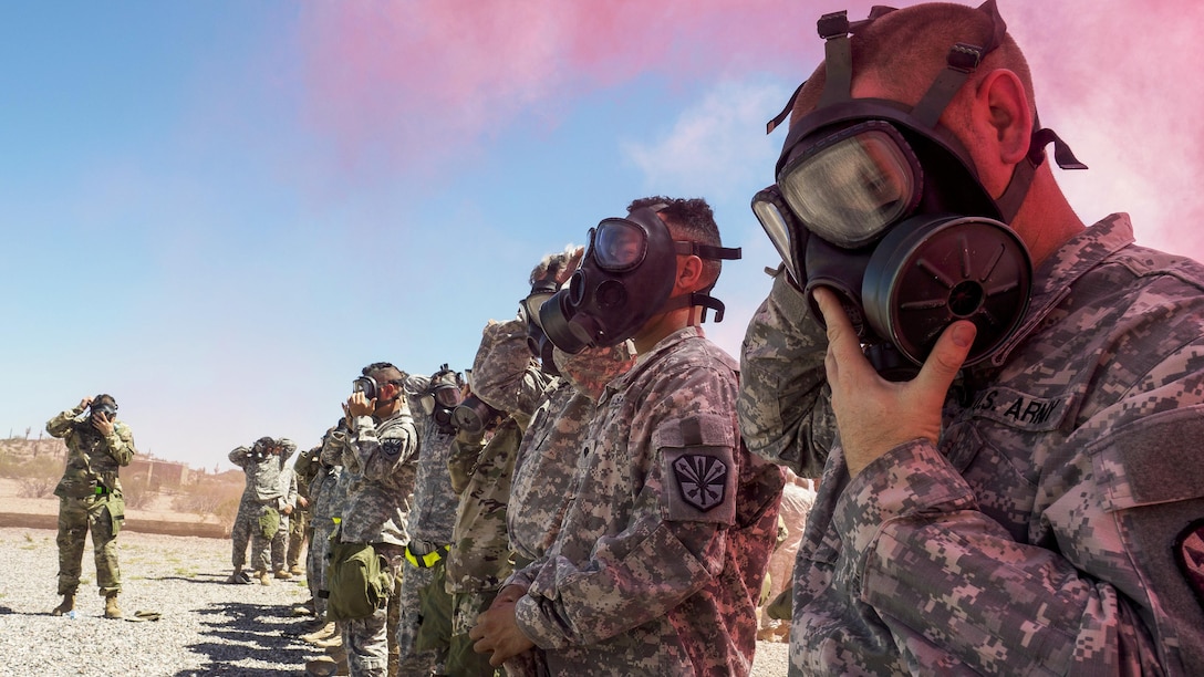 Soldiers wear masks as pink smoke wafts overhead.